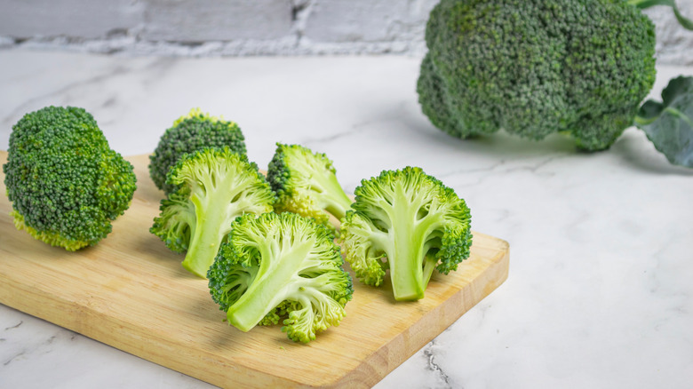 Fresh green broccoli on wooden cutting board, crispy texture, delicious and healthy food, on white marble background.