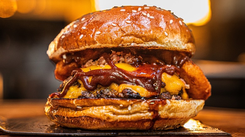 A barbecue smash burger sits on a spatula ready for plating.