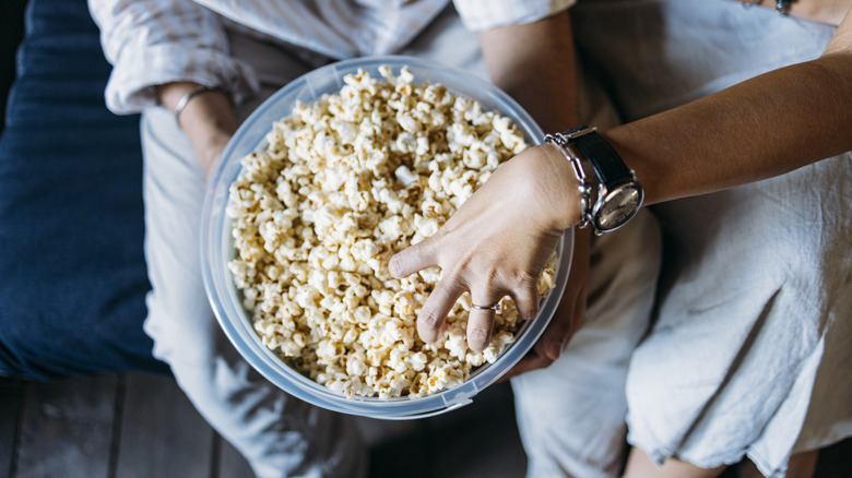 hands reaching into a big bowl of popcorn