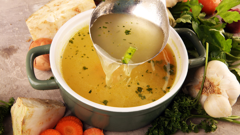 Broth in a pot surrounded by vegetables