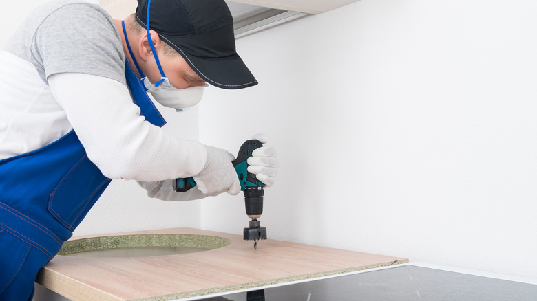worker installing hole for kitchen faucet