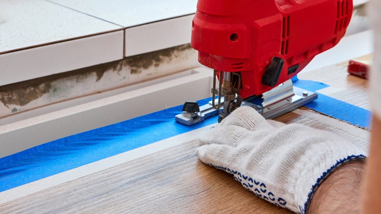 person using a jigsaw to cut a hole in a counter