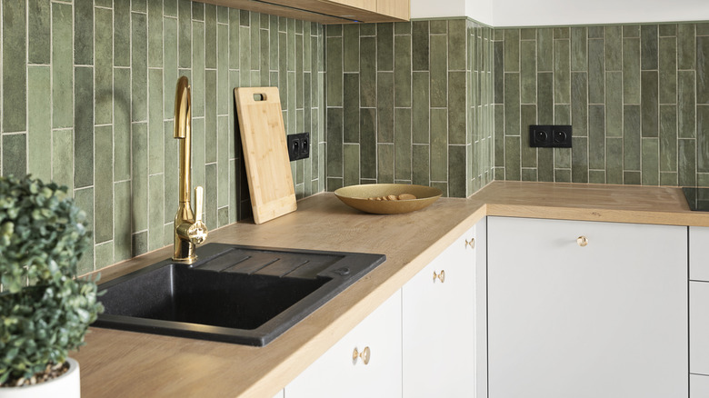 dark gray kitchen sink in modern kitchen with forest green tile