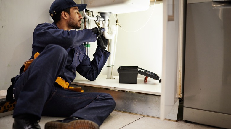 man working under kitchen sink