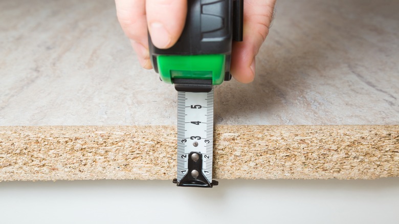 hand measuring thickness of cut countertop