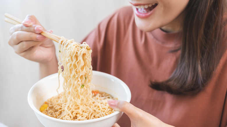 Person having a bowl of instant ramen with chopsticks