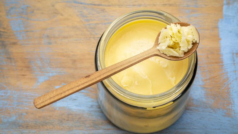 Clarified butter in a glass jar with a wooden spoon photographed from above.