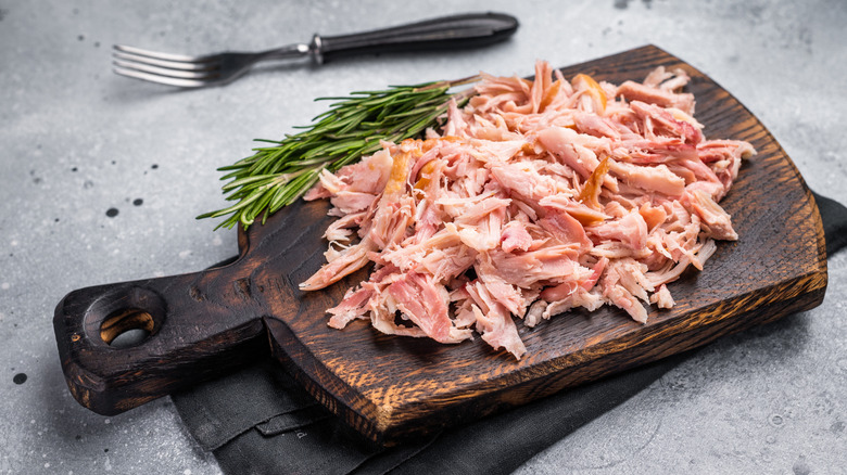 Shredded chicken on a wooden cutting board.