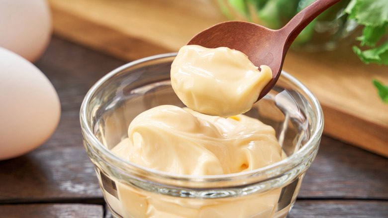 Mayonnaise in a glass dish with a wooden spoon