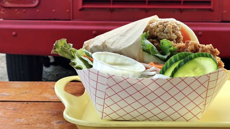 Fresh takeout tray of gyros, sauce, and veggies from food truck