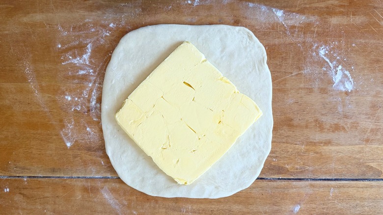 a base dough with a butter block in the center on a wooden table