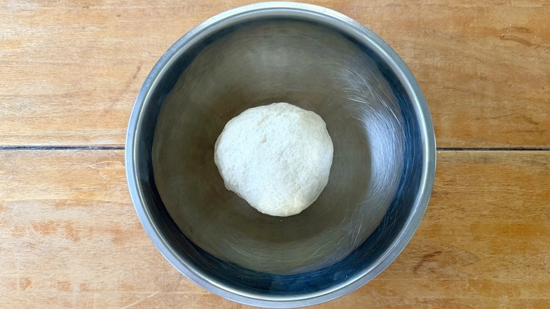 a base dough in a metal mixing bowl on a wooden table