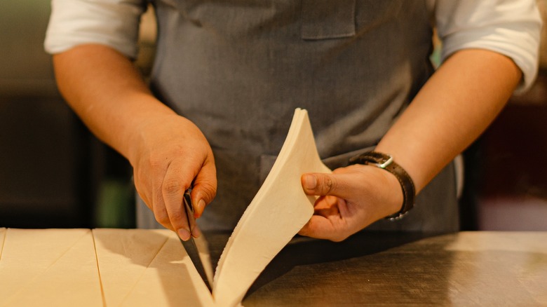 close up shot of pastry chef cutting puff pastry dough