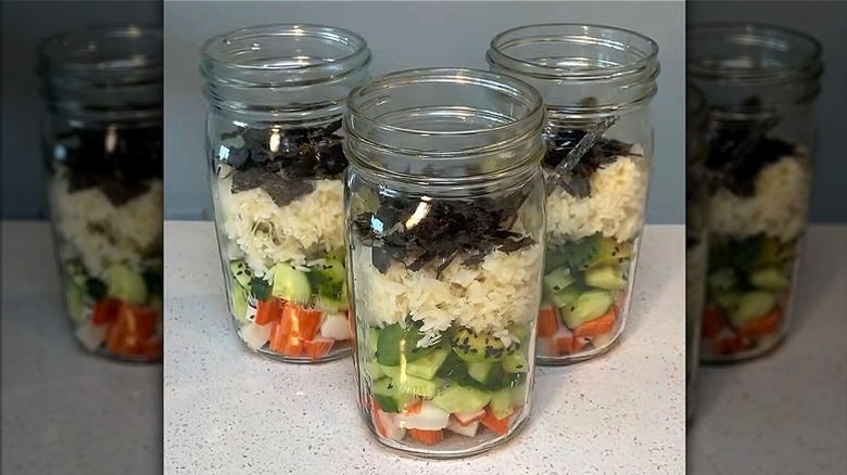 Multiple Mason jars with layered sushi ingredients.