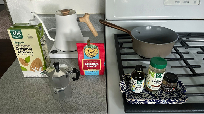 Ingredients for a latte are shown on a counter next to a stove.