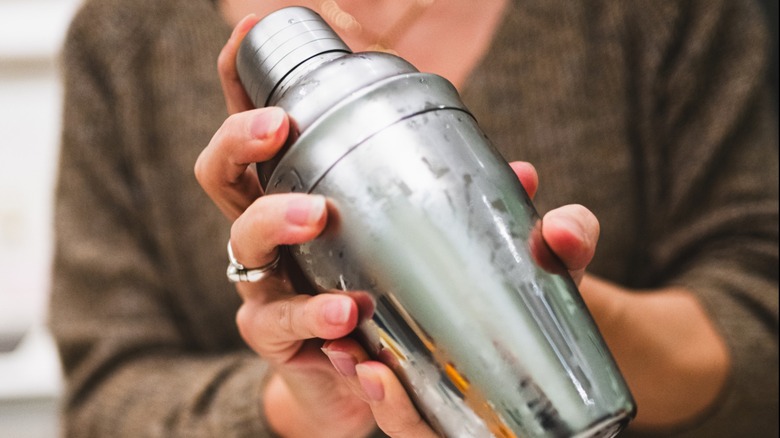 Woman shakes margarita in an ice-cold shaker.