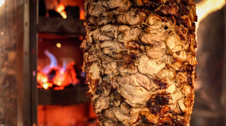 A closeup of meat cooking on a standing rotisserie.