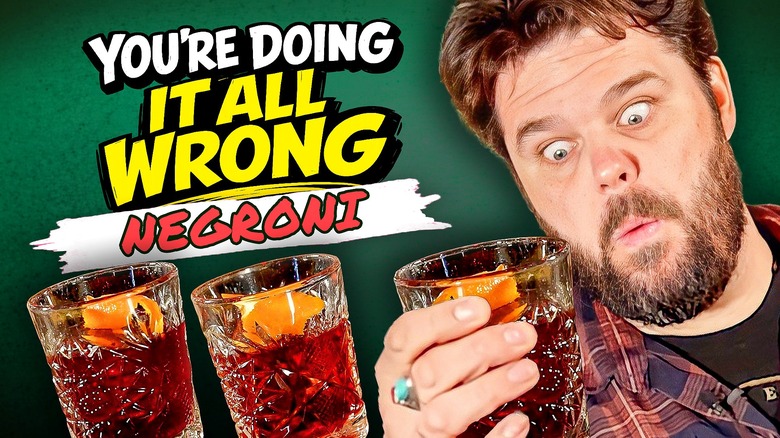 Chowhound's bartender Harry Webler holding a Negroni cocktail with wide eyes