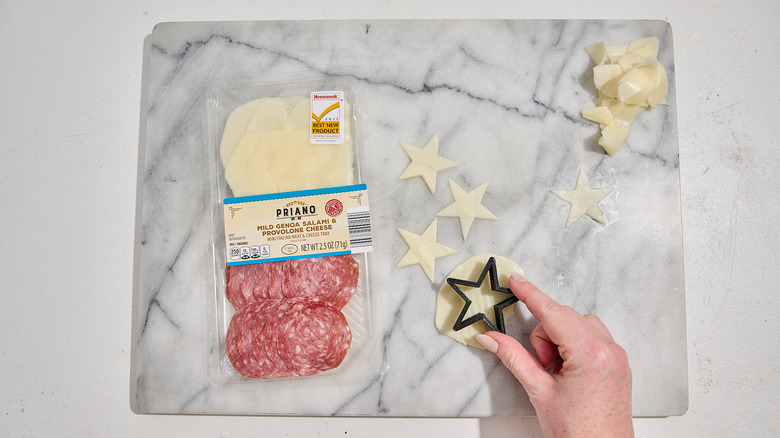 Pressing a star shaped cookie cutter into a slice of cheese