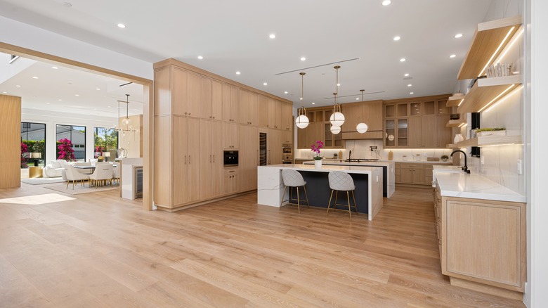 A modern luxury kitchen with light wood cabinetry, large island and open-concept dining area.
