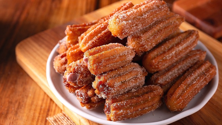 Plate of crispy churros stacked on a white plate
