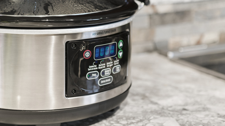 Slow cooker with a fogged lid on a textured kitchen counter