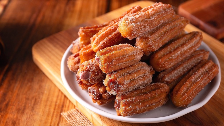 Plate of crispy churros stacked on a white plate