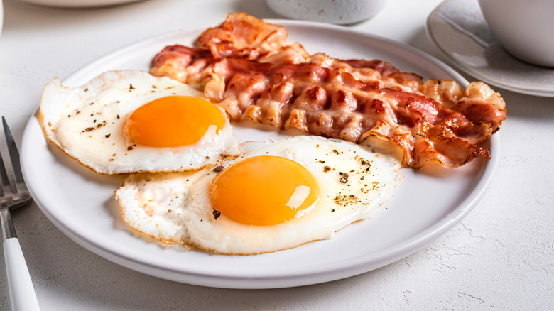 Breakfast with fried eggs and bacon close-up. Fried sunny side eggs with bacon on plate