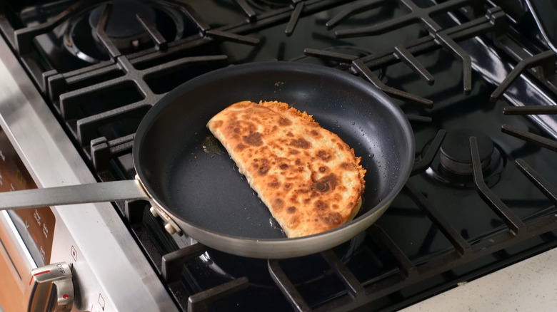 Chef at the kitchen a preparing quesadilla in a pan