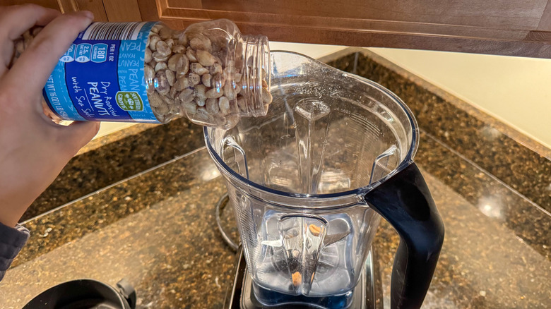 Person pouring peanuts into a food processor