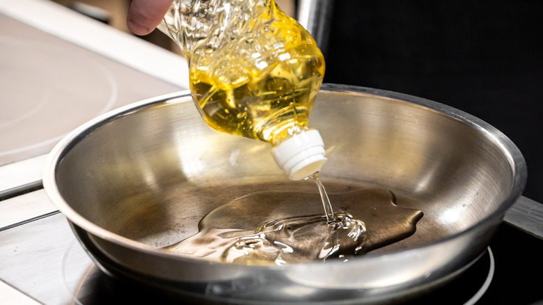 Pouring high heat oil for frying into a skillet