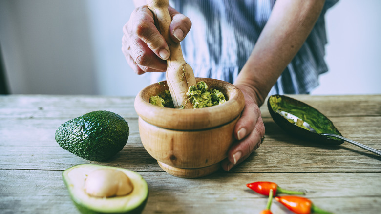 A person making guacamole in mortar and pestle