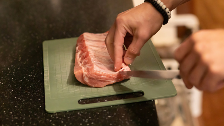 Chef cutting the membrane on rack of pork ribs.