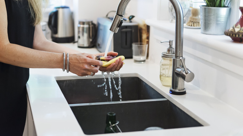 Woman washing carrots in the kitchen sink