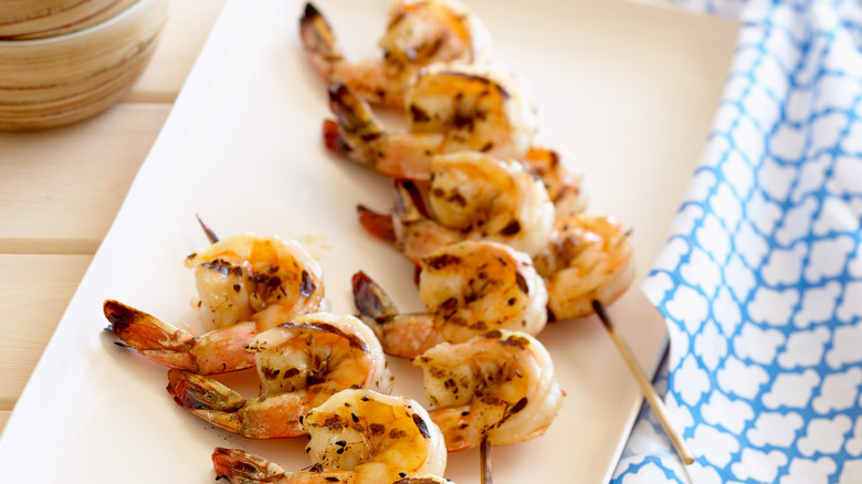 shrimp skewers on white plate with blue towel