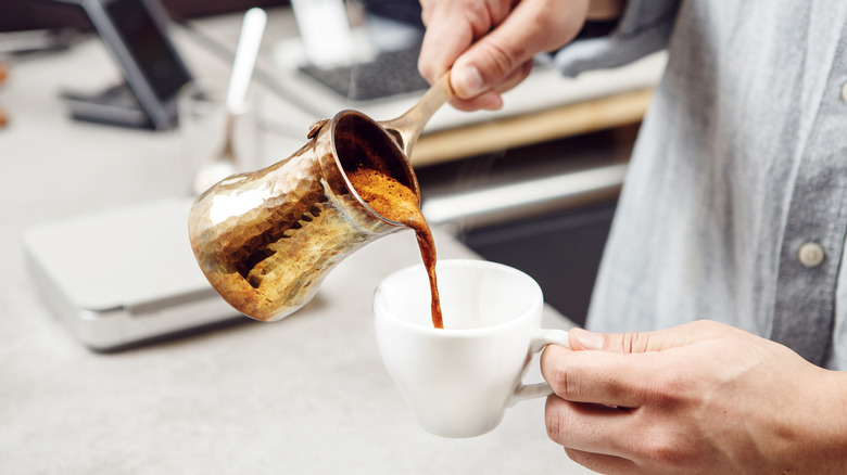 Person making Turkish coffee at home in a cezve