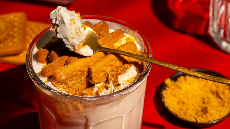 a spoon and a glass with yogurt and cookies