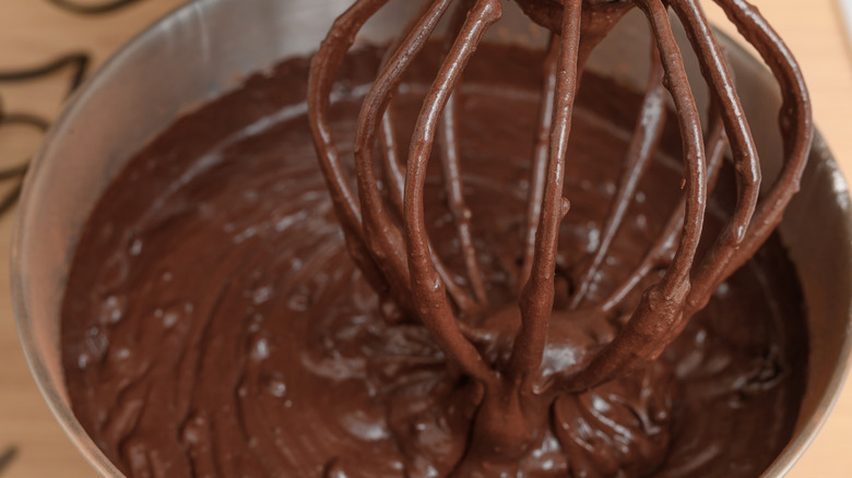 Close up of chocolate cake batter in a stand mixer with the whisk attachment.