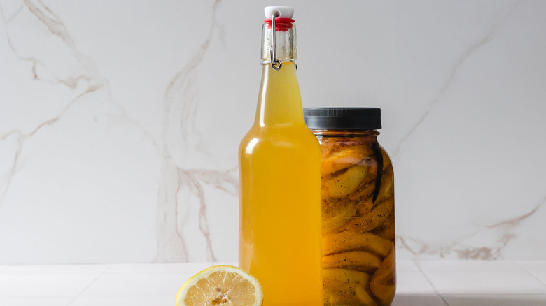A bottle of vodka next to a group of citrus fruits