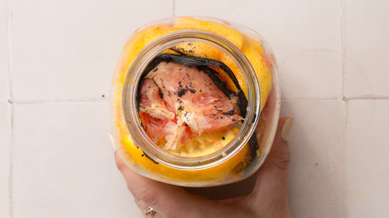 Hand holding jar with citrus and vanilla bean