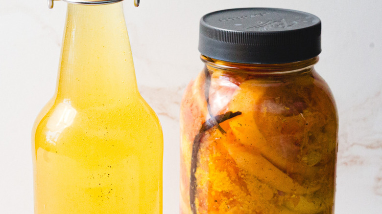 A bottle of citrus flavored vodka near jar and two citrus halves