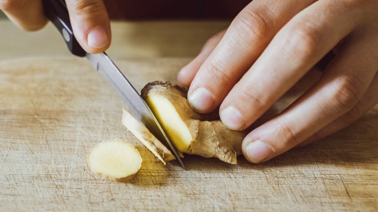 Hands slicing ginger