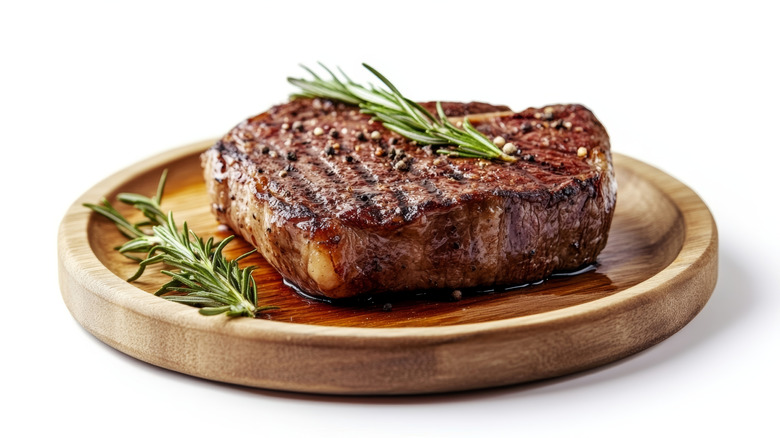 steak and rosemary on wooden plate
