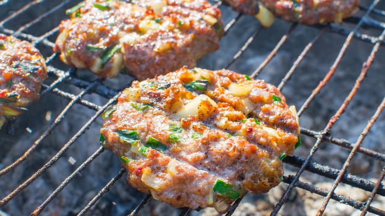A burger grilling over charcoal