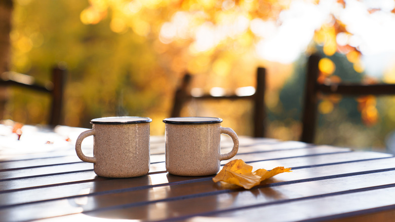 Pumpkin lattes in mugs on a table in autumn