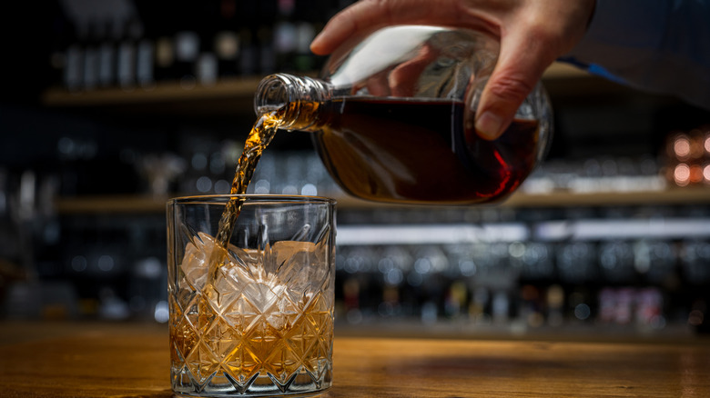 A man pouring whiskey into a glass.