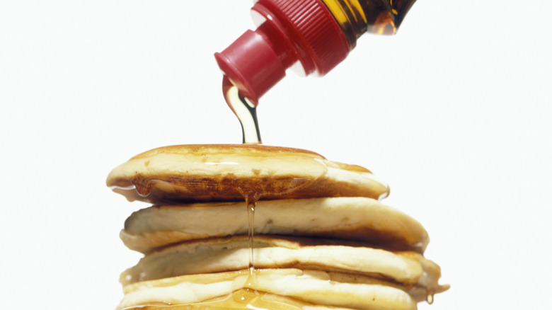 bottle of maple syrup squirting onto pancakes