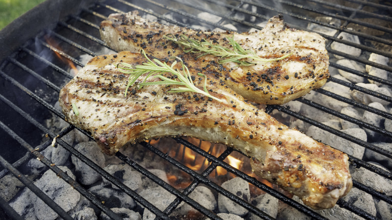 two thick seasoned pork chops on a grill