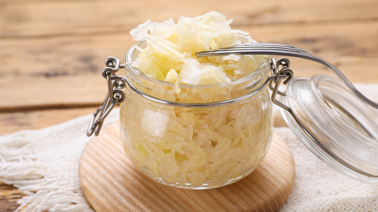 A fork rests on a jar of pickled cabbage or sauerkraut
