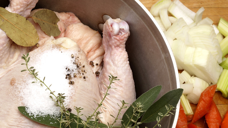 A whole chicken in pot prepared to be poached